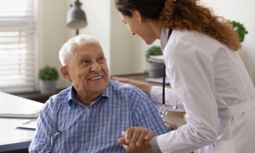 Une infirmière soutient le bras d'un homme âgé avec bienveillance.