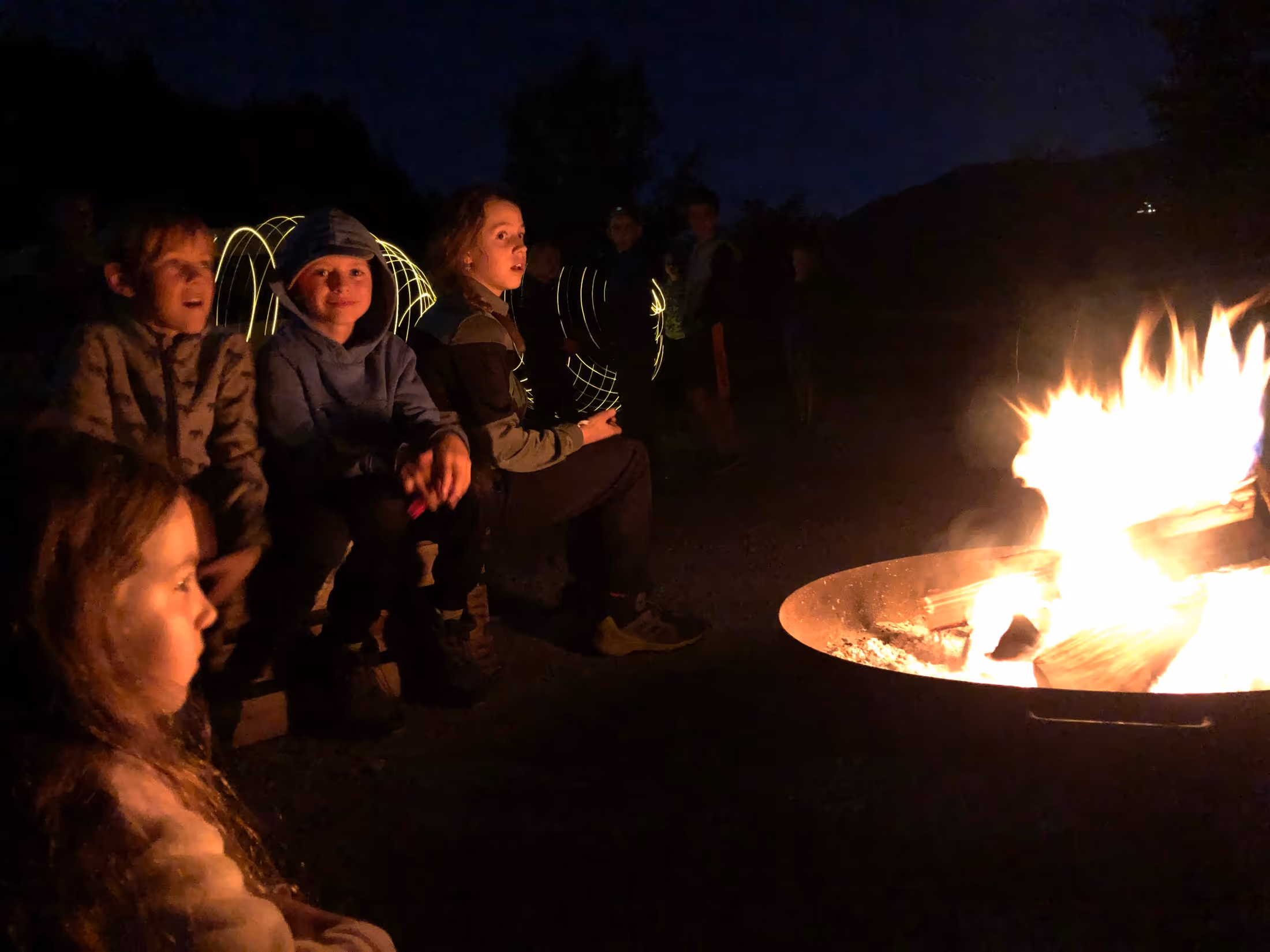 Familie geniesst die Stimmung am Lagerfeuer.