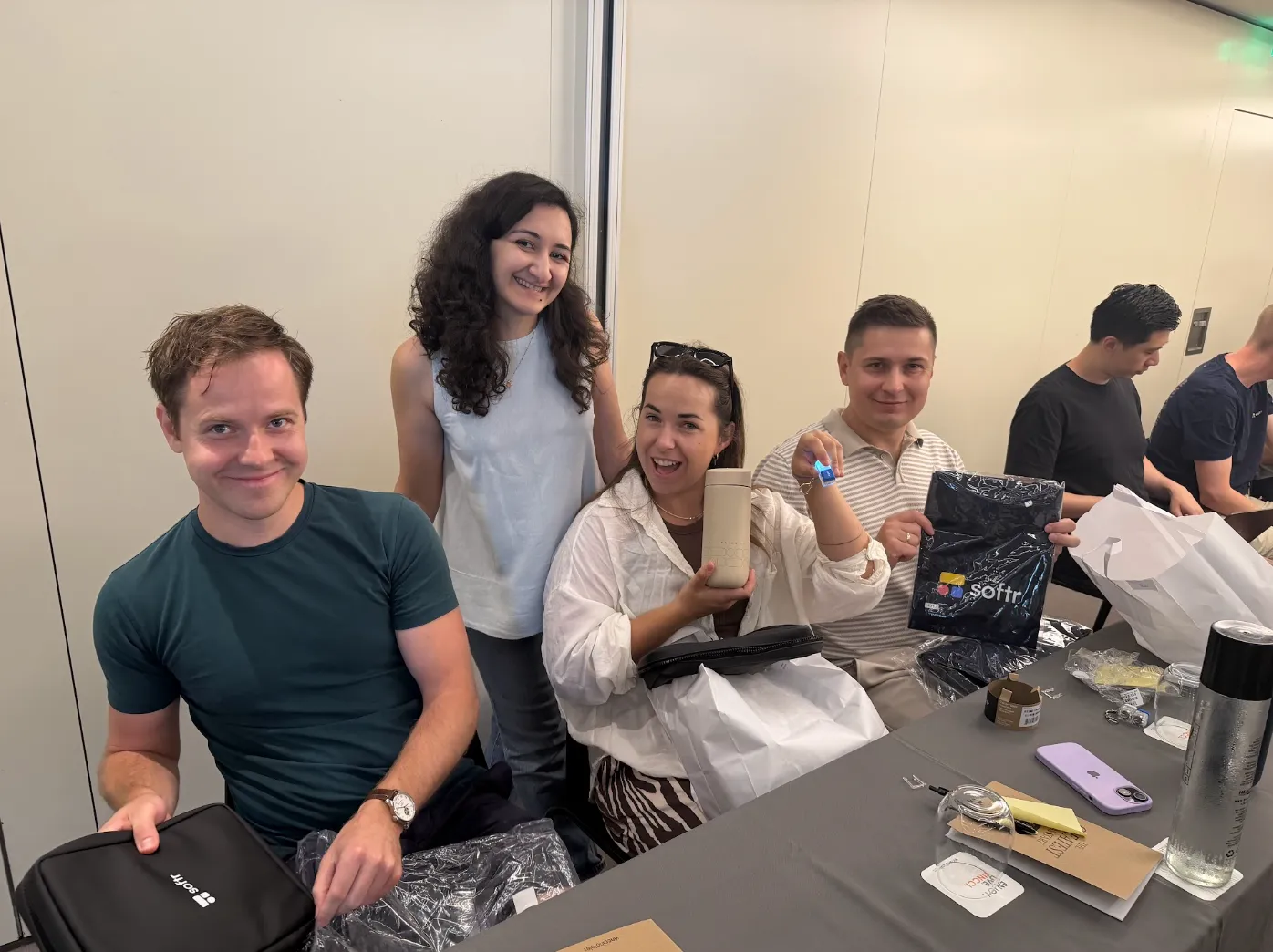 Four Softr teammates smiling around a table while unpacking Softr-branded swag