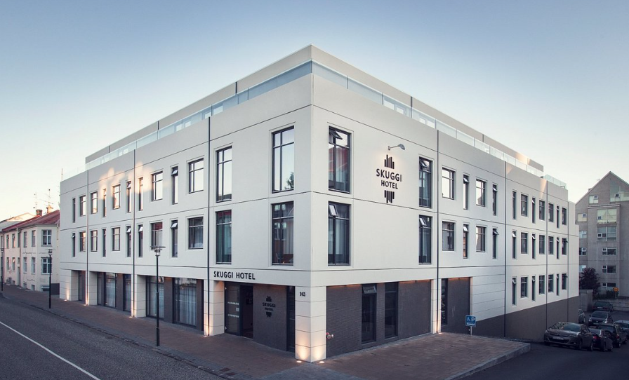 Hotel Skuggi, a white four-storey corner building on a quiet Reykjavik street at dusk