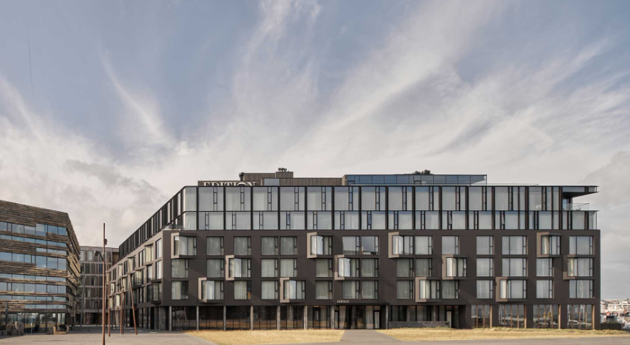 The Reykjavik EDITION, a dark glass and stone hotel on the old harbour under a wide sky
