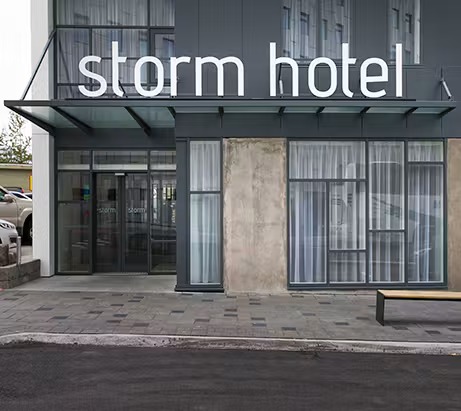 Storm Hotel entrance with a white 'storm hotel' sign above glass doors on a dark grey and concrete facade
