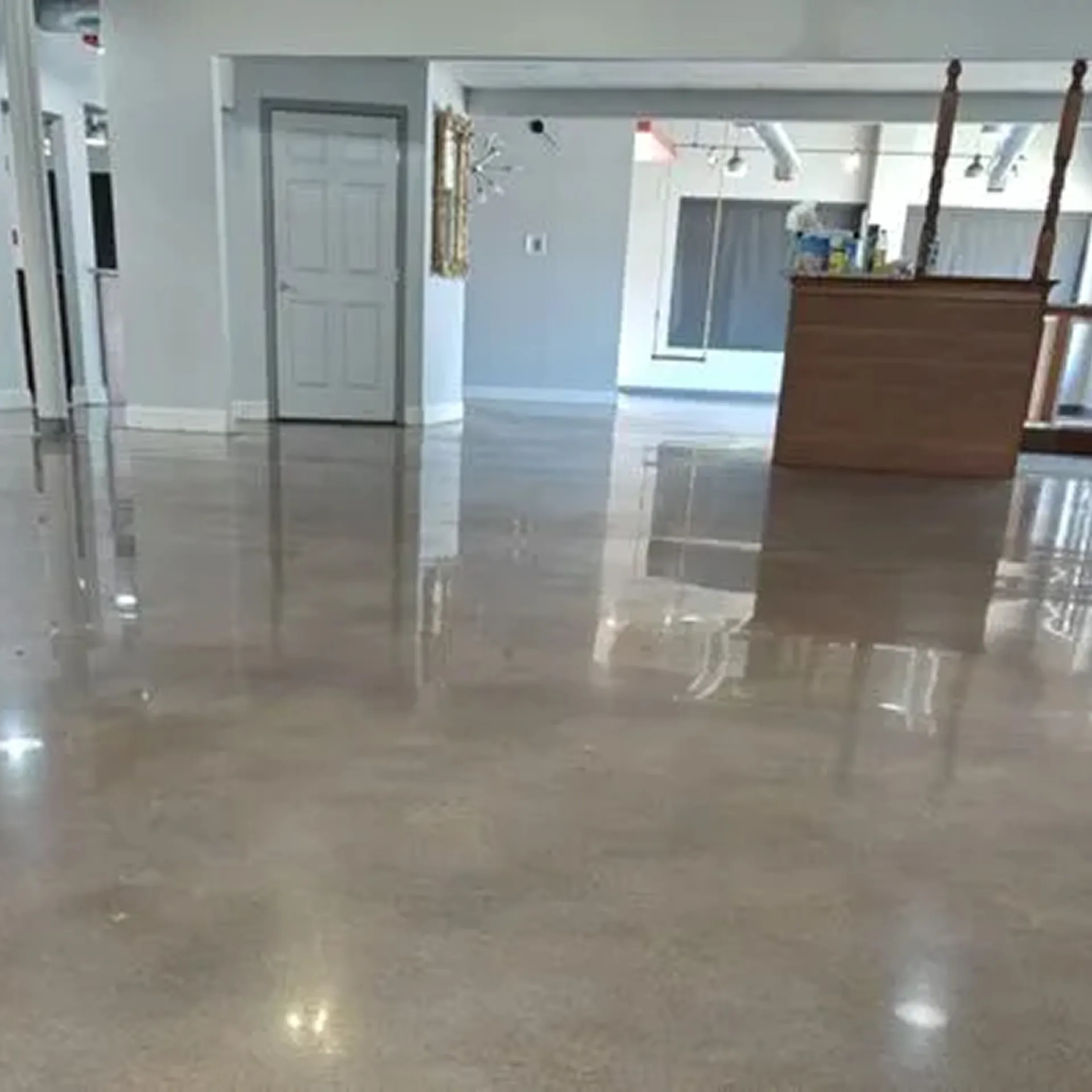 Worker operating a concrete polishing machine on an unfinished floor in a building under construction.