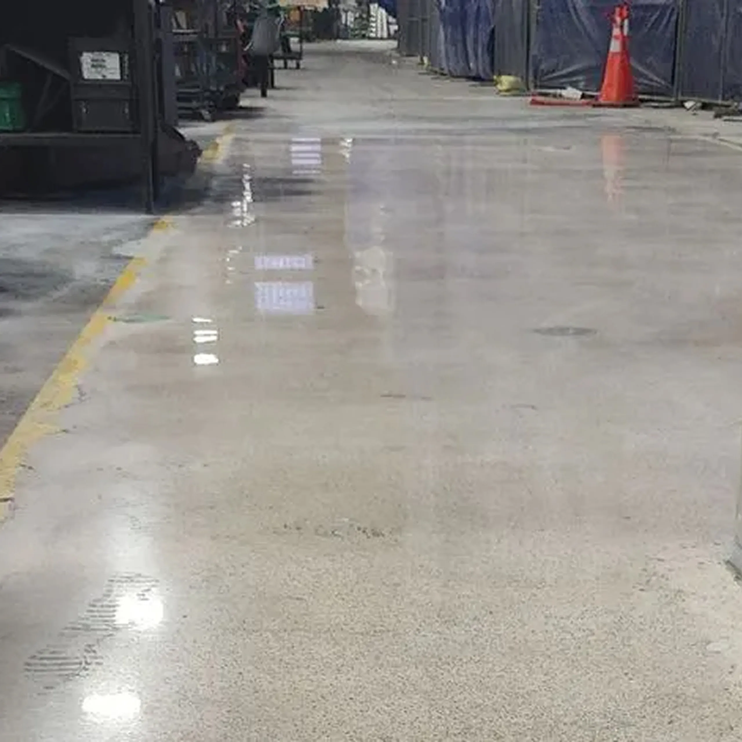 Worker operating a concrete polishing machine on an unfinished floor in a building under construction.