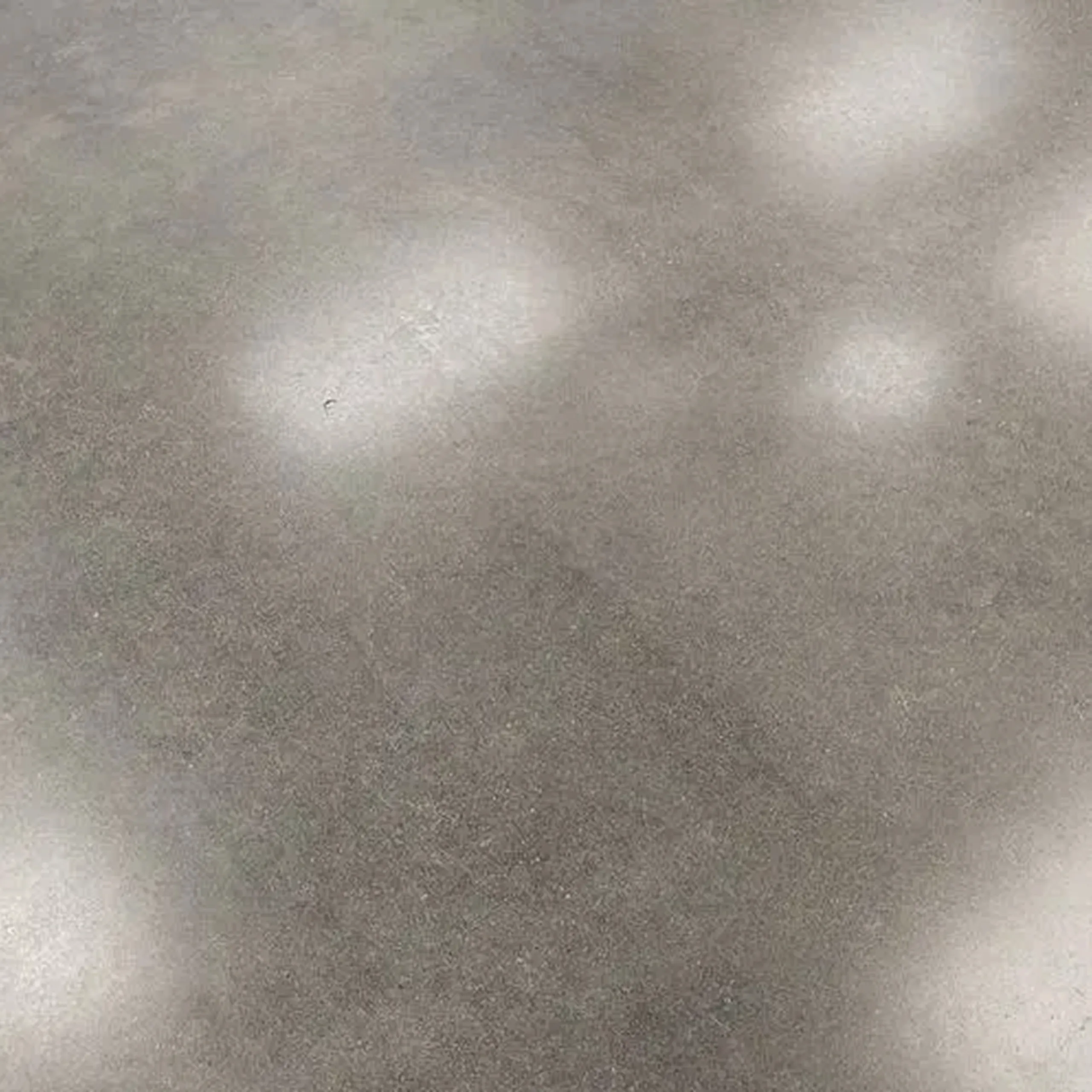 Worker operating a concrete polishing machine on an unfinished floor in a building under construction.