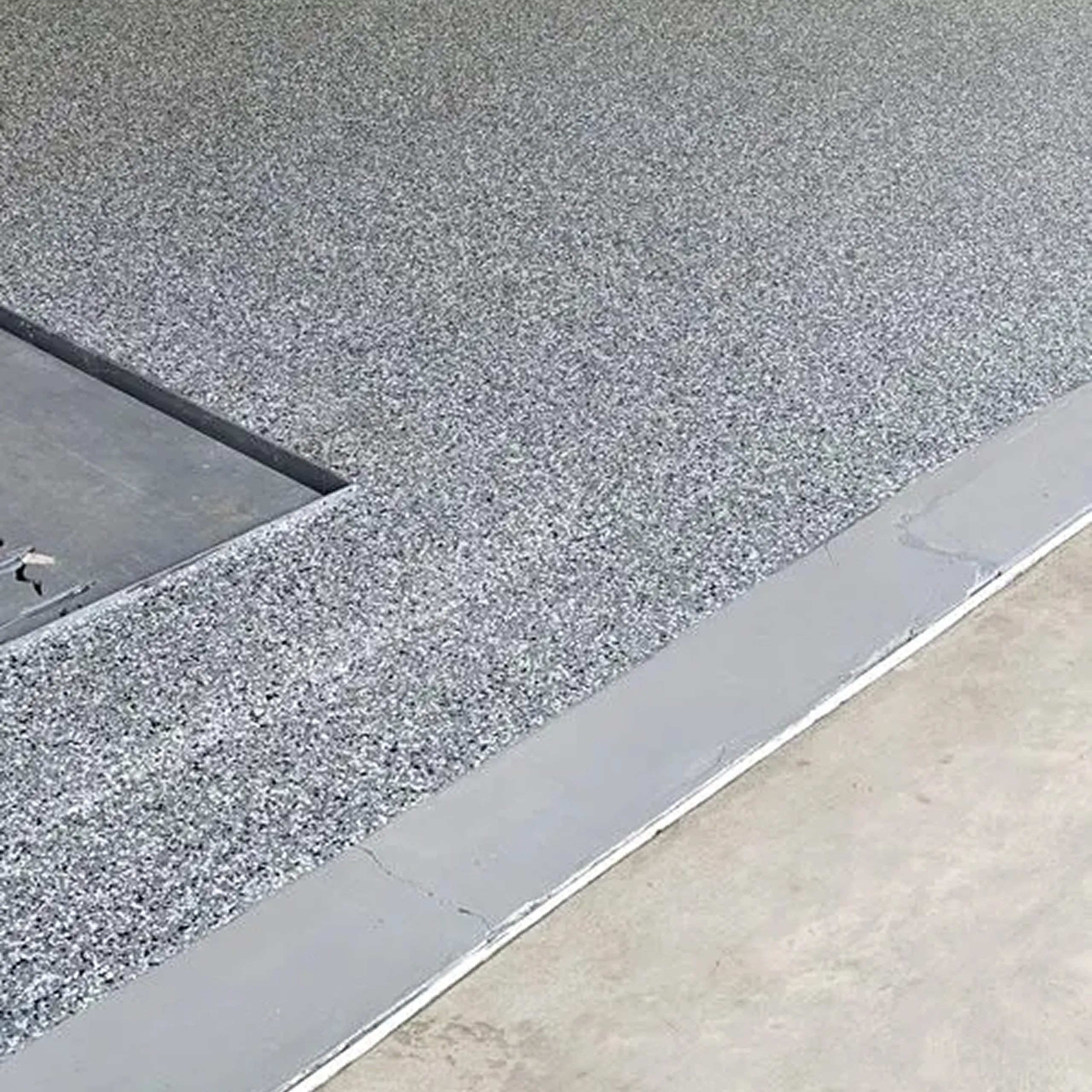 Worker operating a concrete polishing machine on an unfinished floor in a building under construction.