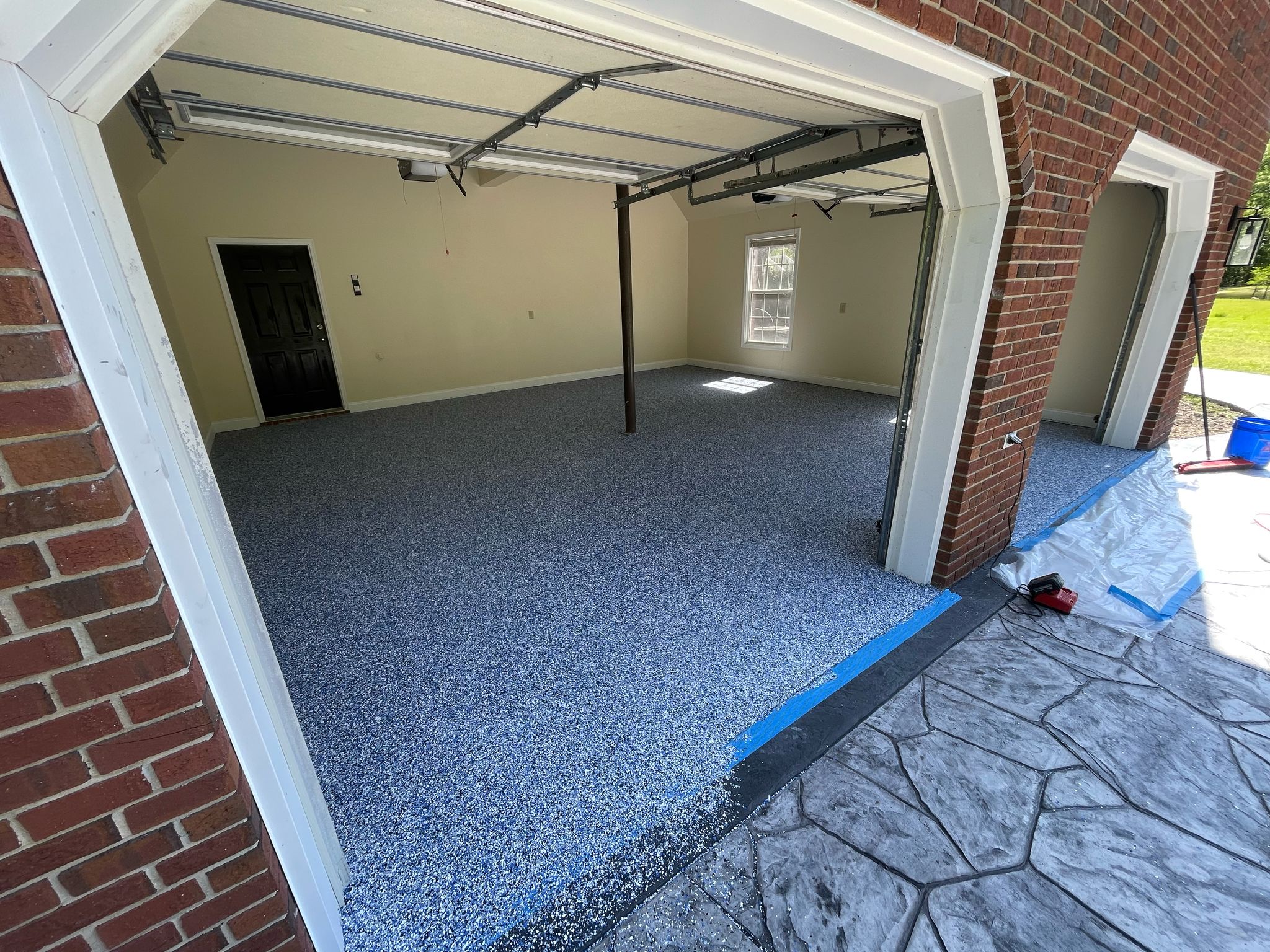 A section of dark gray textured stone tiles arranged in a rectangular pattern on a light gray concrete surface.