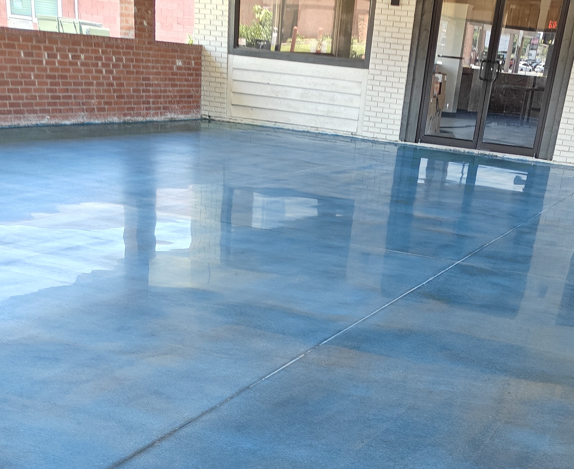 Person operating a floor polishing machine on a shiny, polished concrete floor.