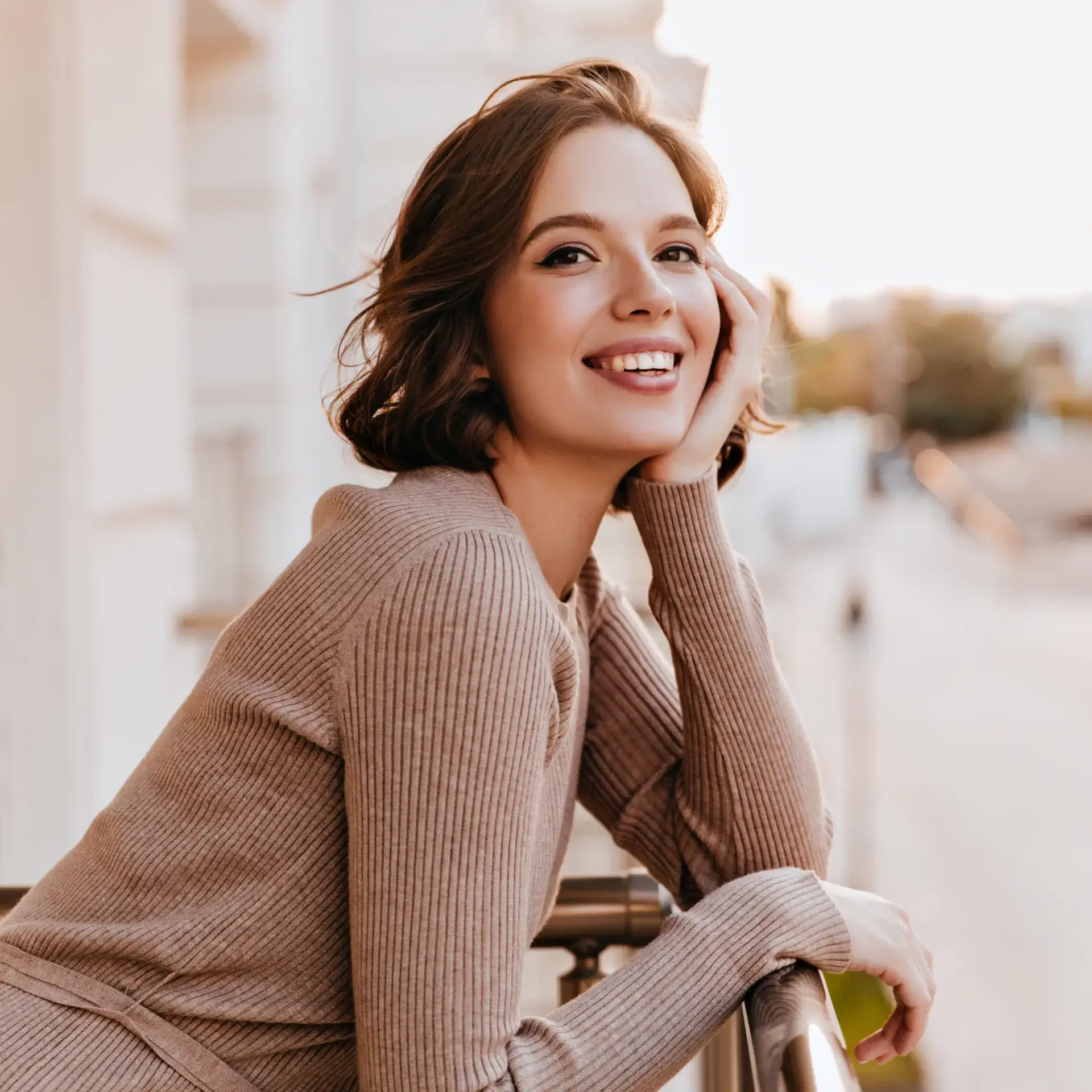 A woman leaning on a rail smiling at the camera.