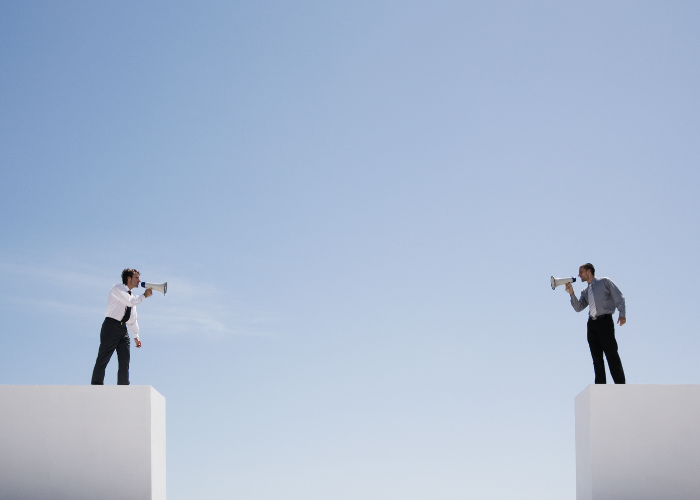Two people screaming with a megaphone over a cliff