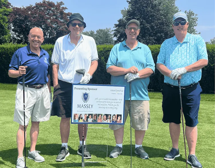Family wearing green standing in front of a wall with illustrations of beer, shamrocks, and horseshoes holding paper cutouts of various St Patricks Day themed objects.