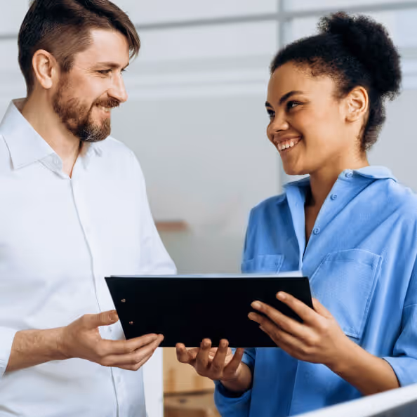 Man and woman discussing a document on a clipboard while standing up
