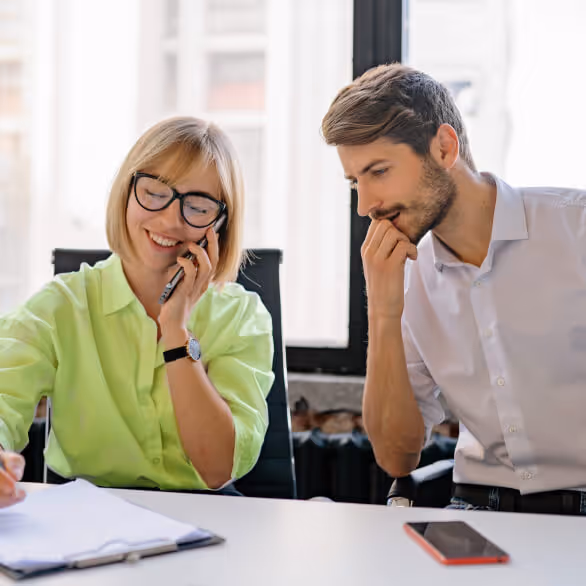 blond lady taking a call on a mobile phone with male colleague next to her