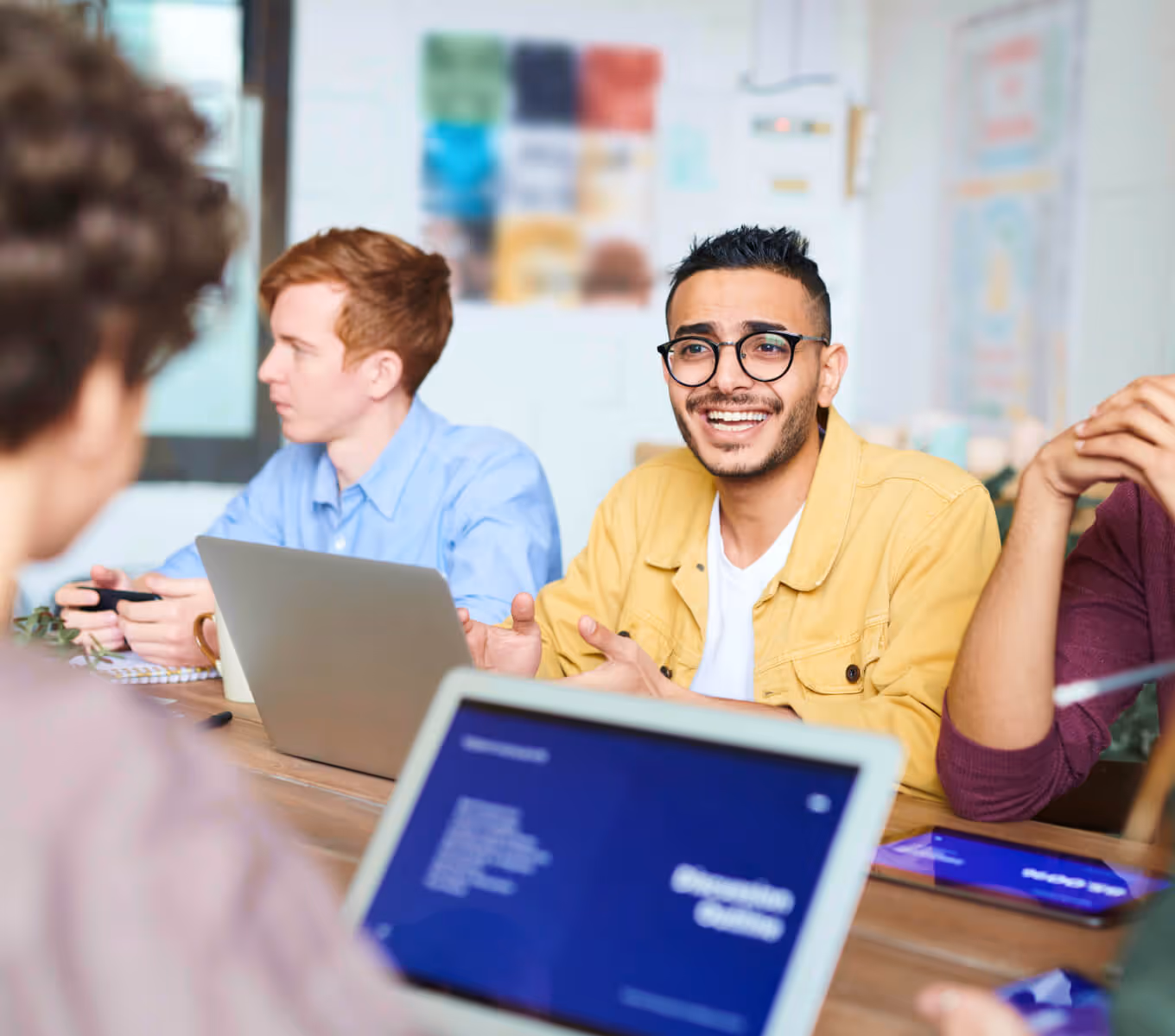 A young man with his team members, sat at a table having a meeting