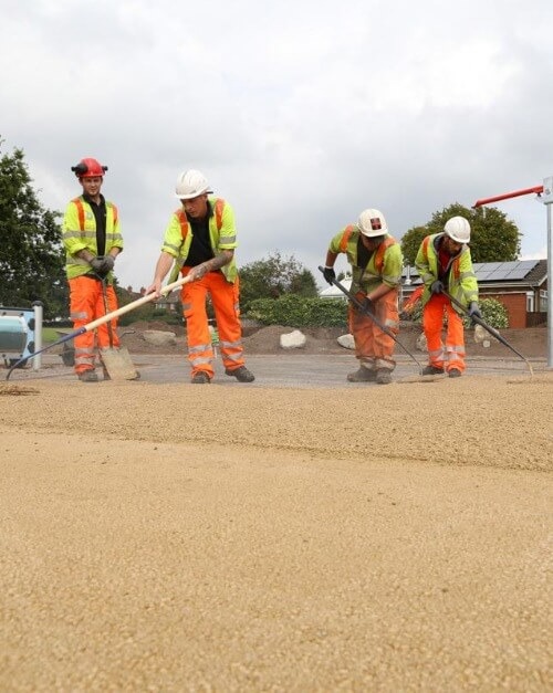 Surfacing crew hand-finishing a newly laid sports ground surface