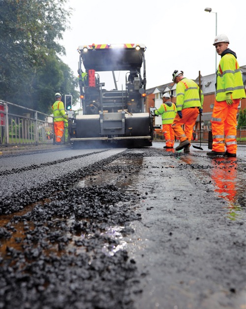 Operated paver laying a new asphalt surface beside a footpath