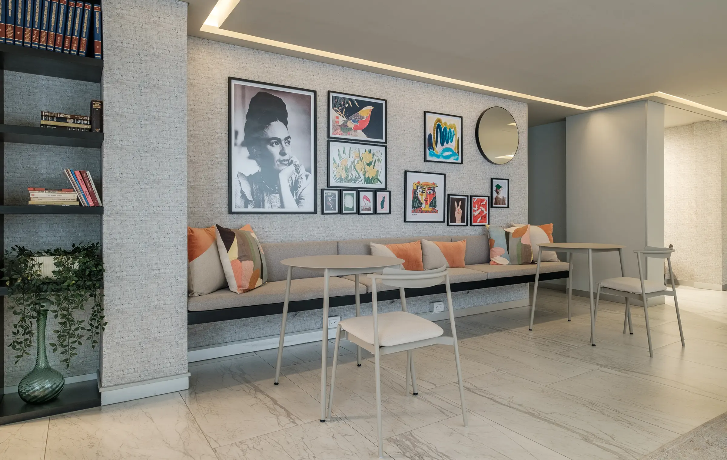 Modern lounge with bench, pillows, art, and tables.