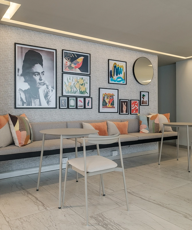 Modern lounge with bench, pillows, art, and tables.