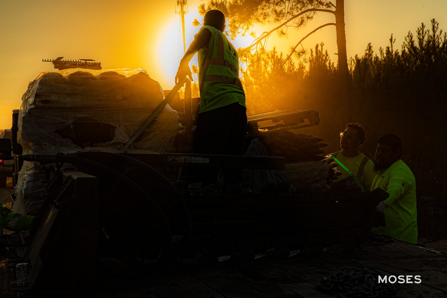 Workers efficiently unloading materials against a stunning sunrise at Old Cuyler Rd in Bryan County, GA, highlighting the teamwork and dedication of Moses Grass Company amid the active construction site.