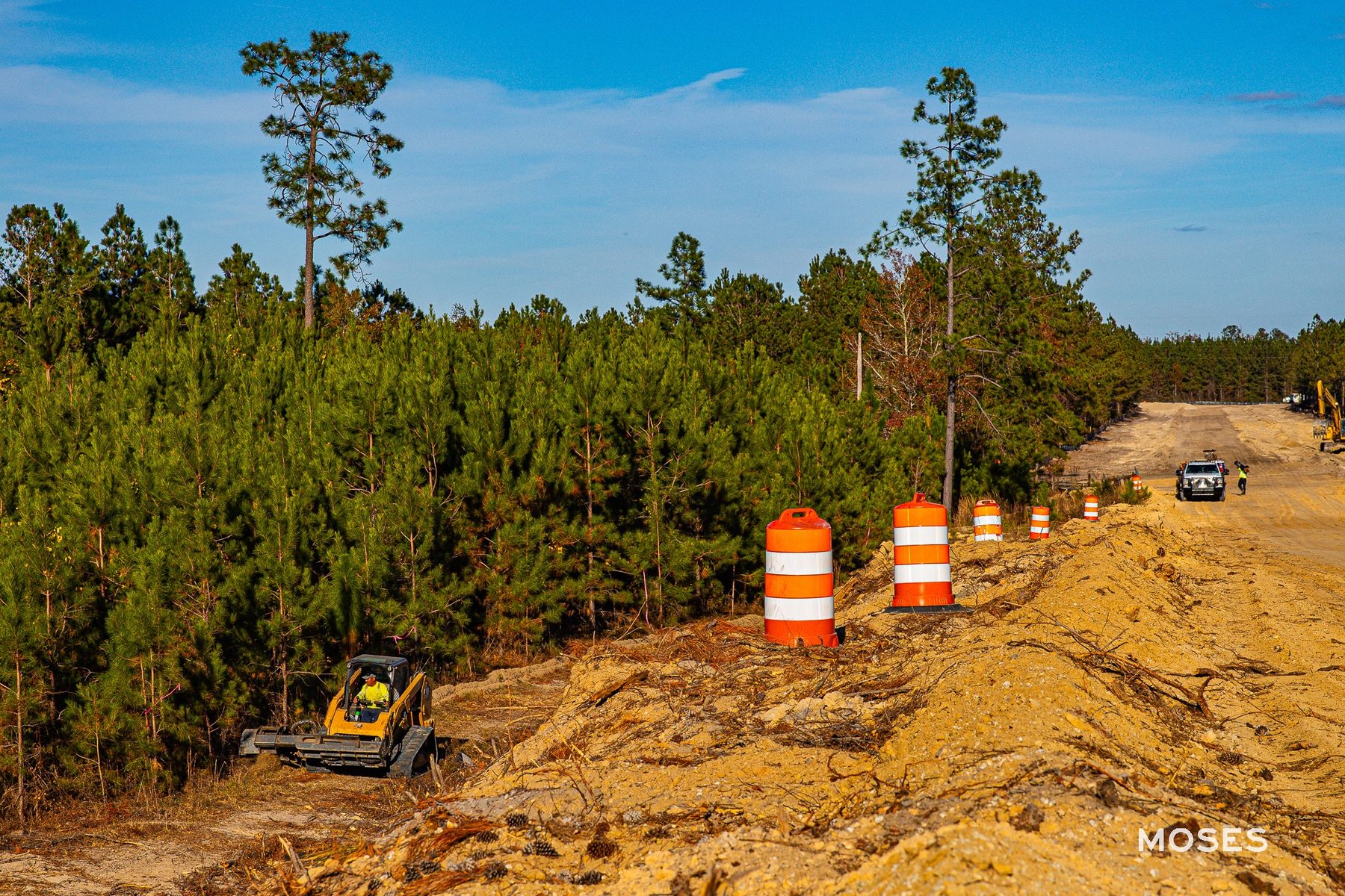 A construction vehicle prepares the site along Old Cuyler Rd in Bryan County, GA, with safety cones marking the area as Moses Grass Company enhances erosion control near the I-16 and Hyundai Metaplant.