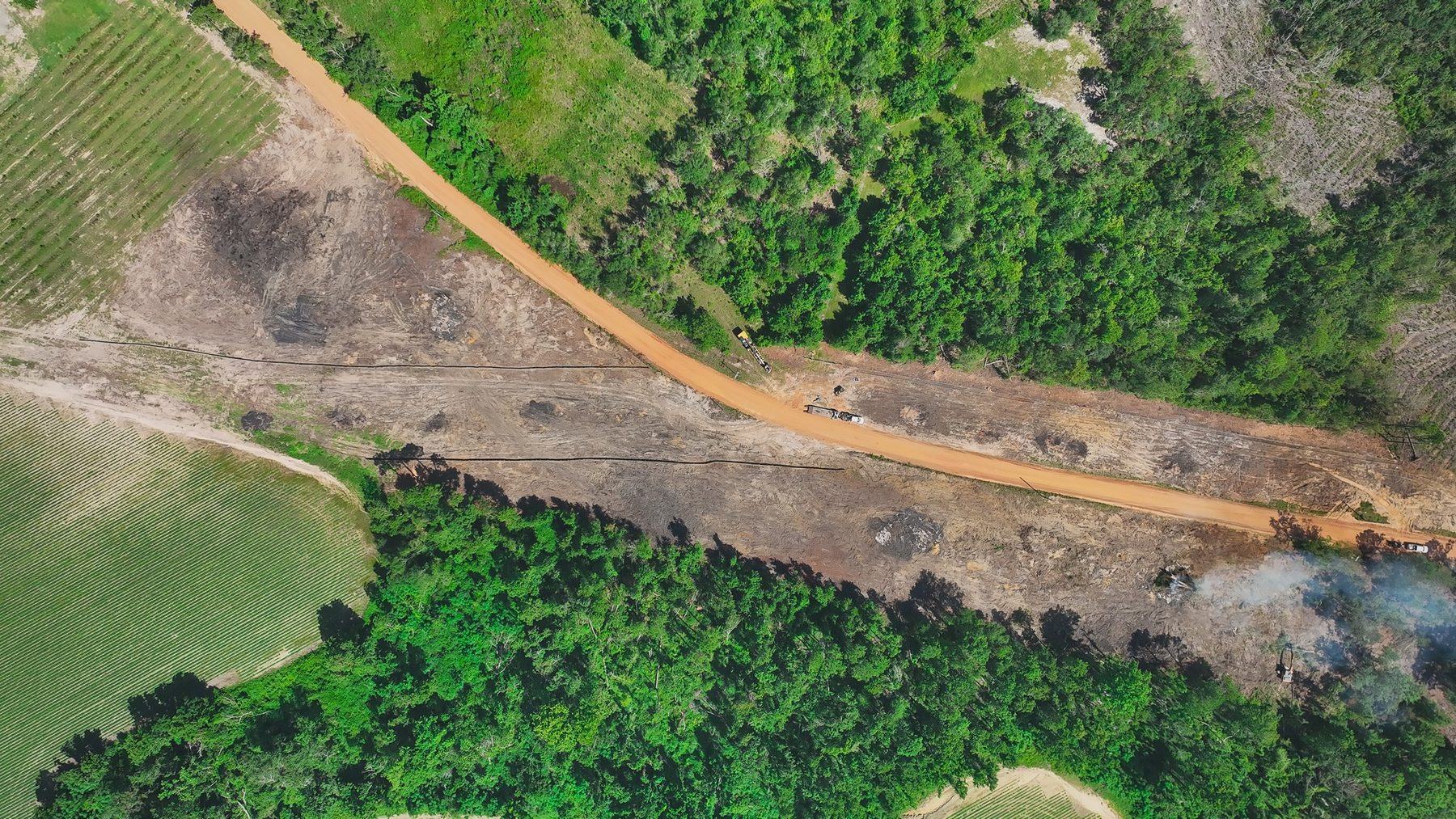 **Alt Text:** Aerial view of Hammond Church Road in Lyons, GA, showcasing site preparation with silt fences installed alongside areas of newly laid temporary grass. The landscape contrasts cleared land with lush green forest, emphasizing...