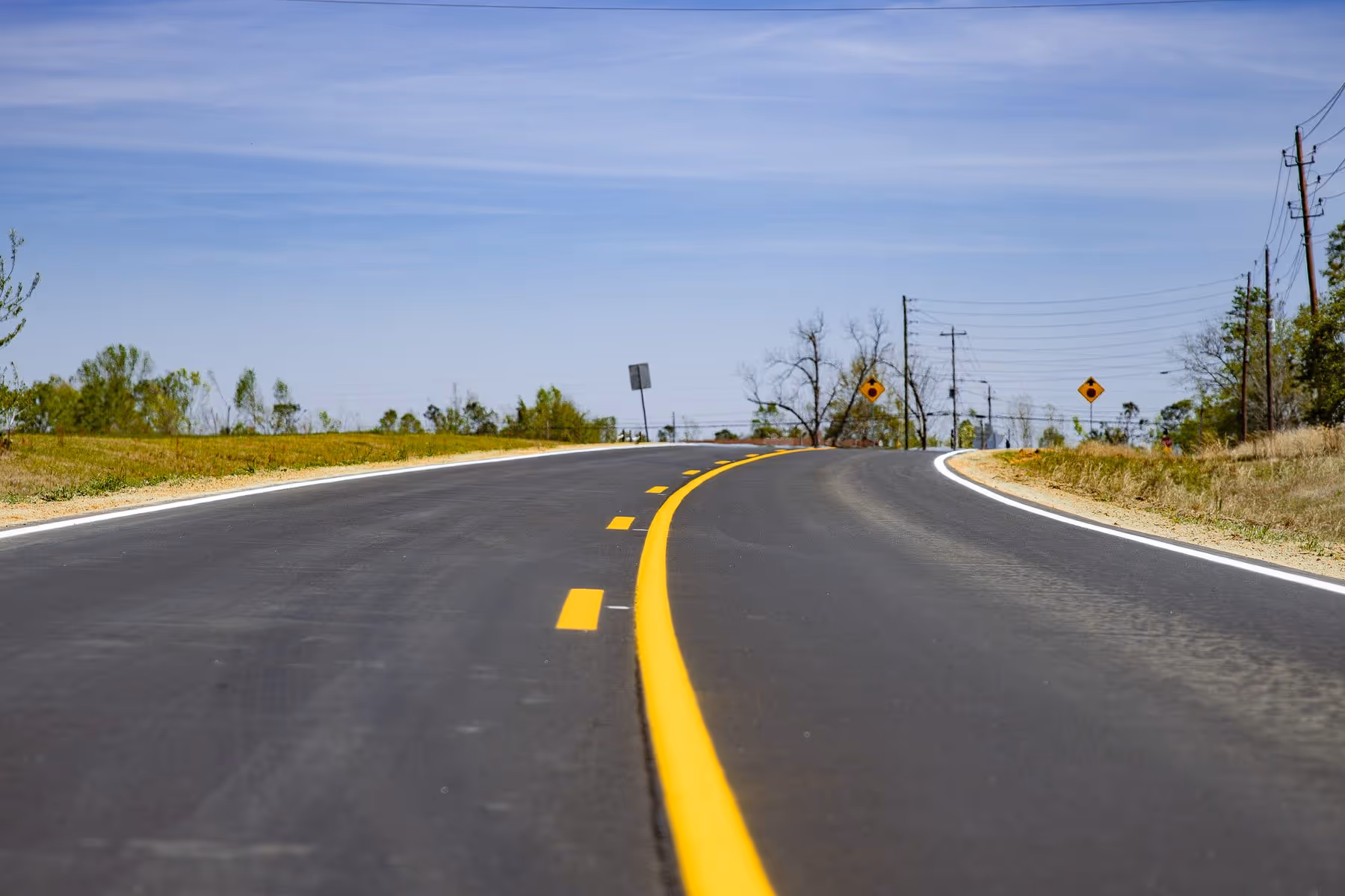 A newly paved curve on Saw Mill Rd in Mount Vernon, GA, showcasing freshly applied striping and hydroseeding for the TIA-LMIG project. We're committed to enhancing road safety and promoting land stewardship. Questions? We’re glad to expl...