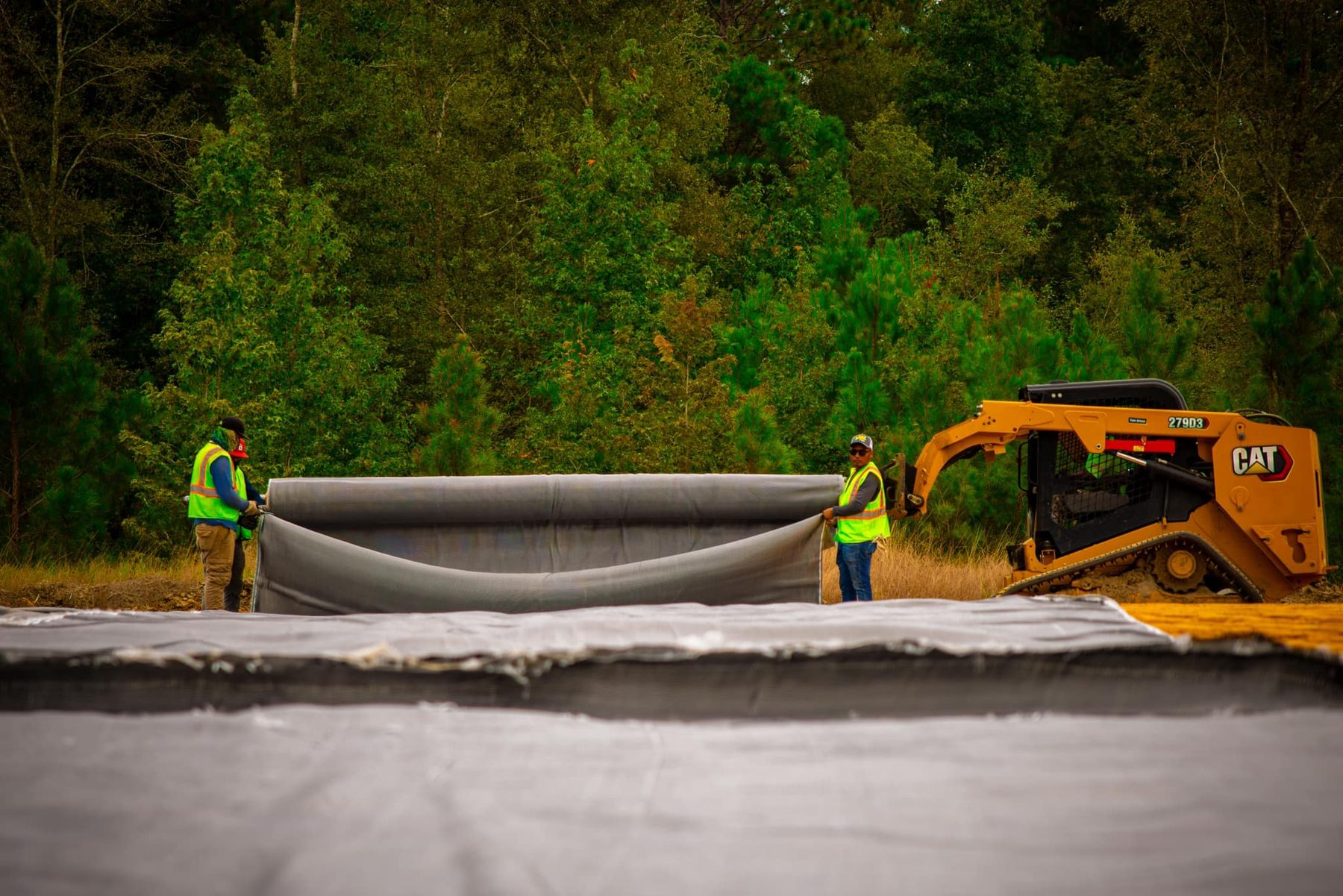 Two crew members are carefully maneuvering large geotextile fabric on the US 1 Bypass project in Toombs County, GA. This stabilization work is essential for erosion control, ensuring a safer and more reliable infrastructure for the commu...