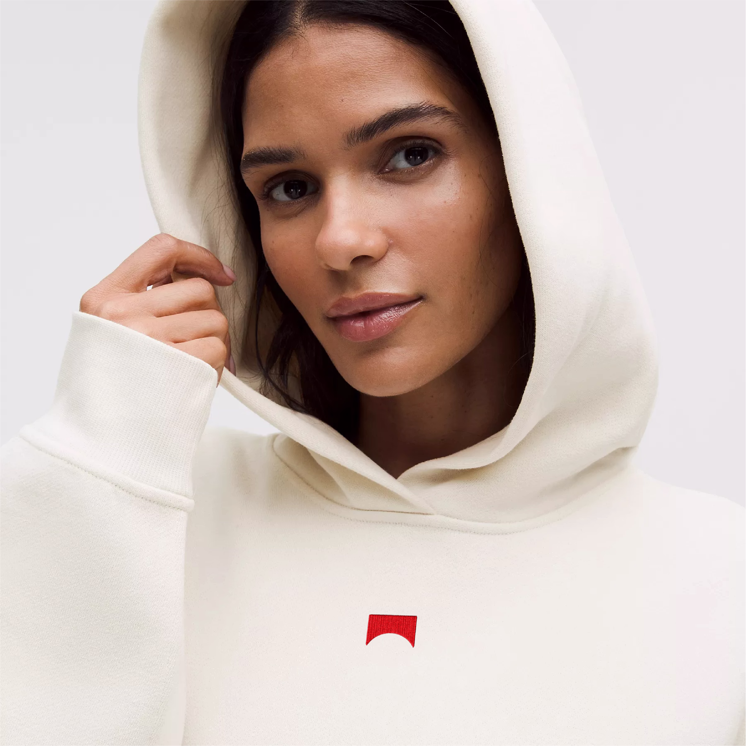 Portrait shot of a woman wearing a cream hoodie with the hood up.