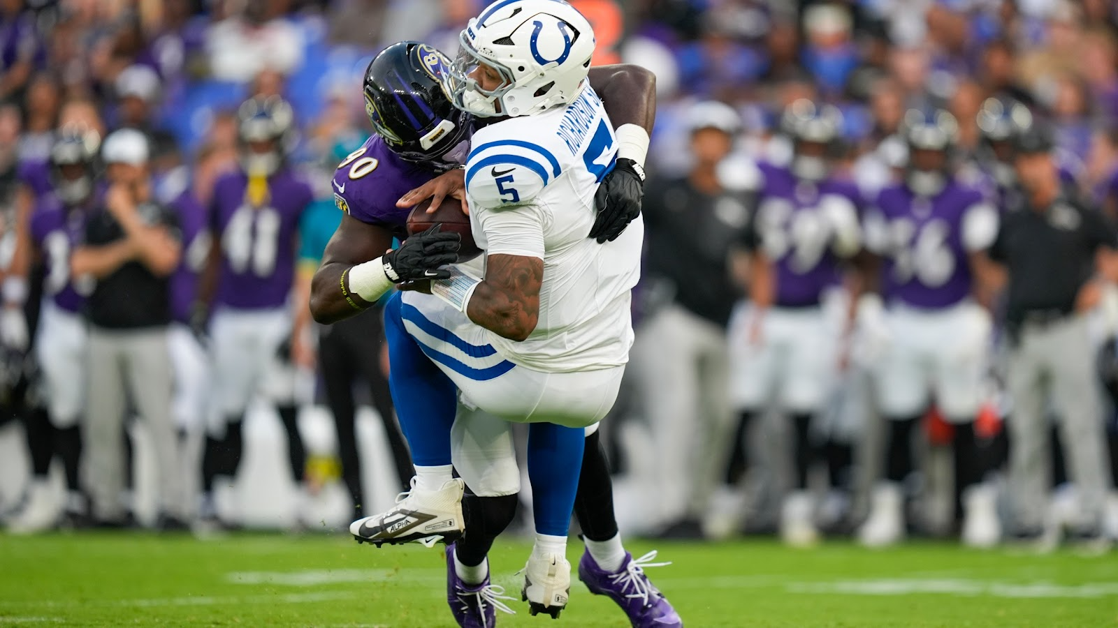Anthony Richardson (5) in de witte Indy Colts jersey wordt getackeld door een Baltimore Ravens player (90).