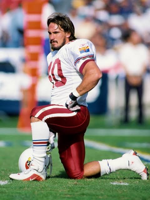 Pat Tillman (40) in Arizona Cardinals gear zit op één knie op het veld.