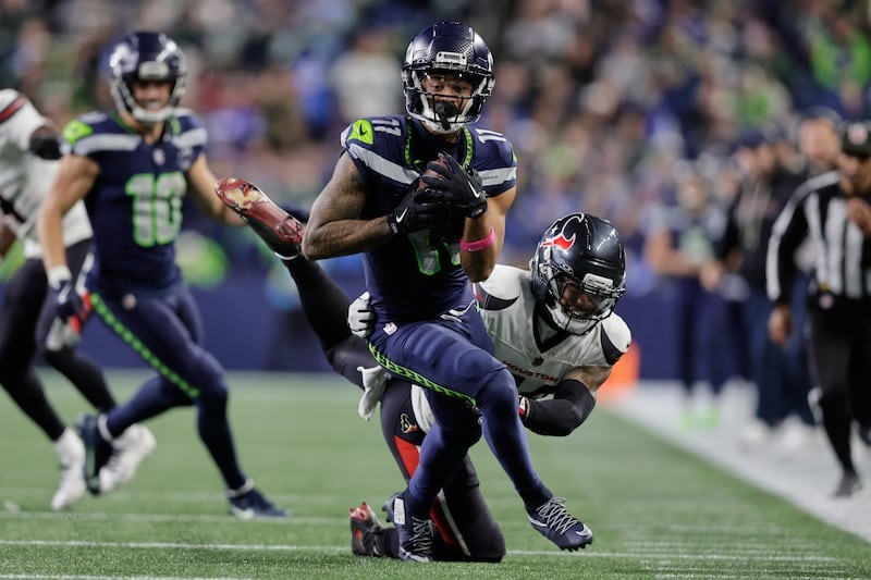 Jaxon Smith-Njigba die na de catch extra yards probeert de maken tegen de defense van de Houston Texans.