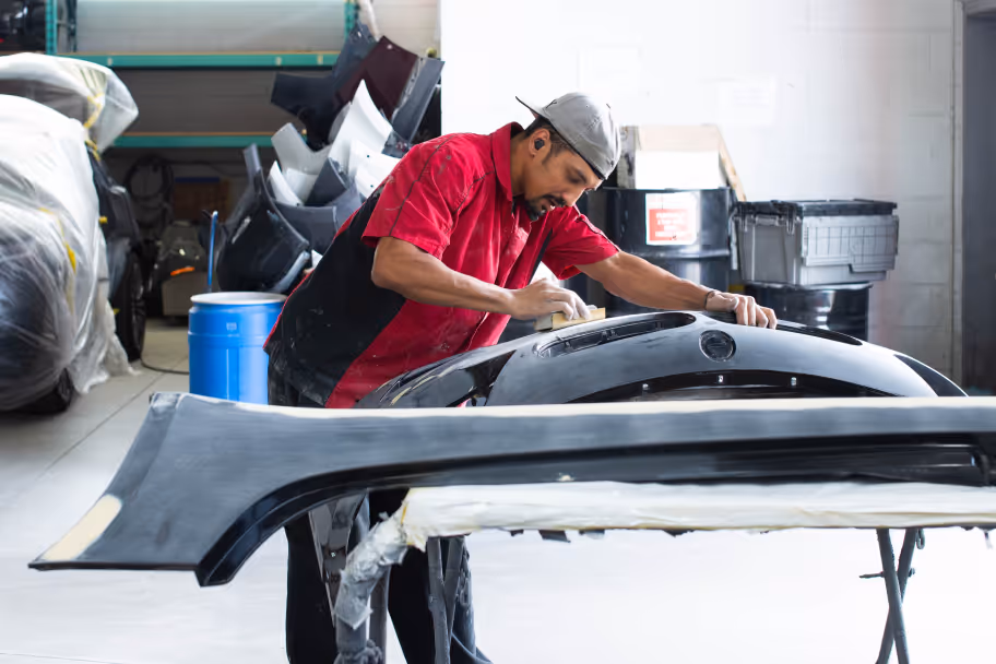 A technician sanding a front bumper