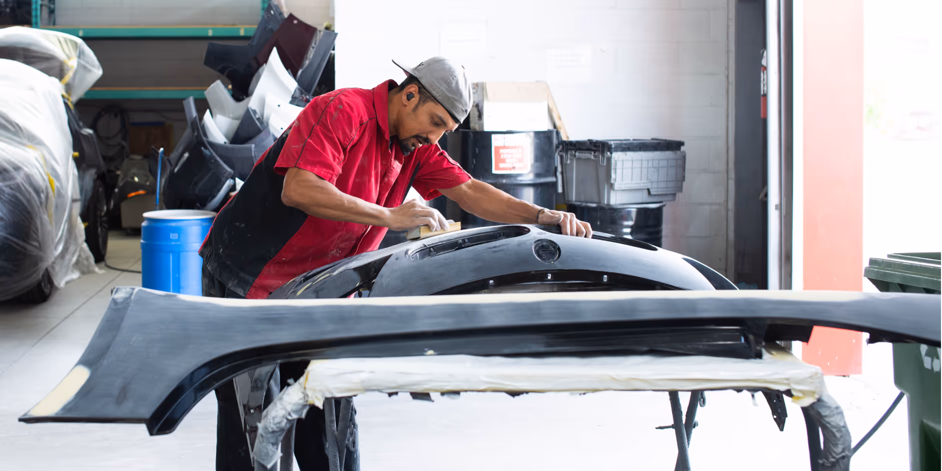 A technician sanding a front bumper