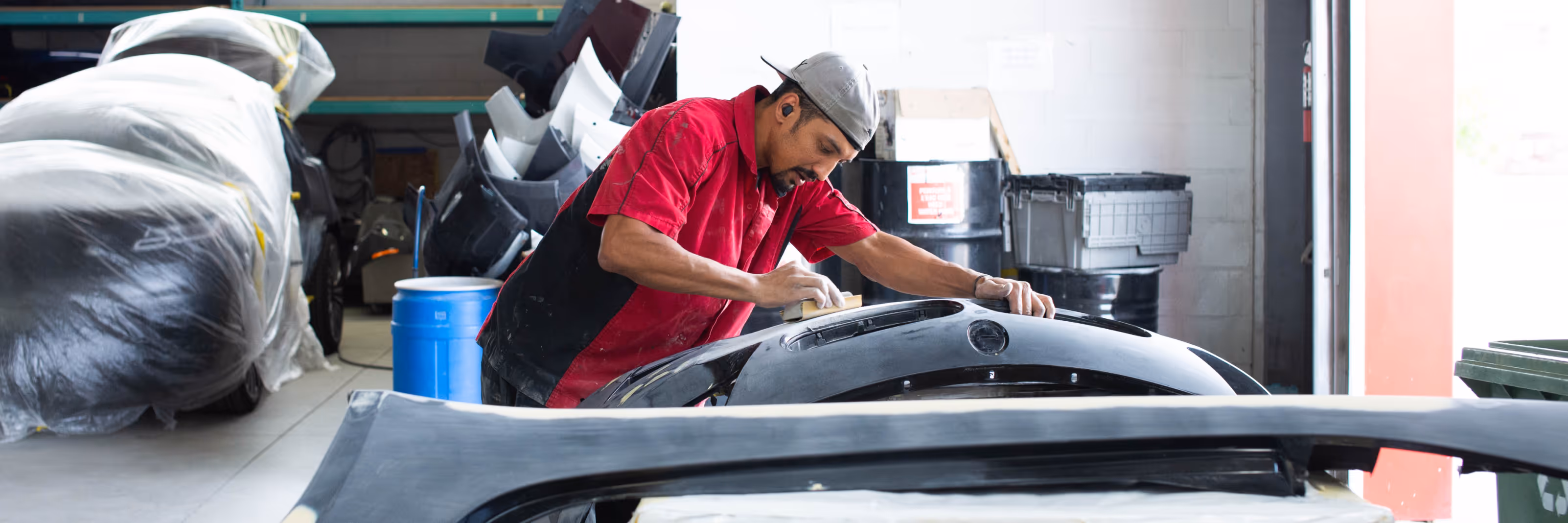A technician sanding a front bumper