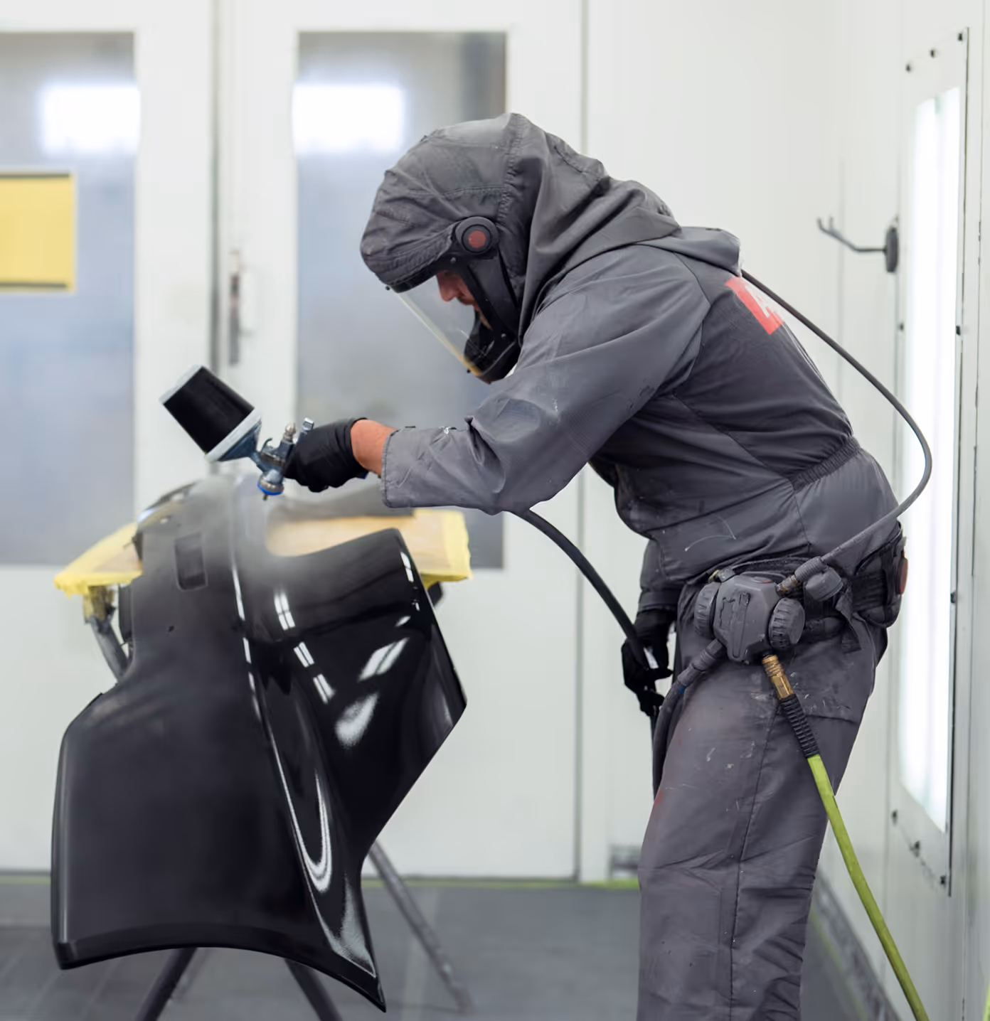 A technician or painter repairing and painting a damaged bumper from a vehicle that’s been in an accident or fender bender.