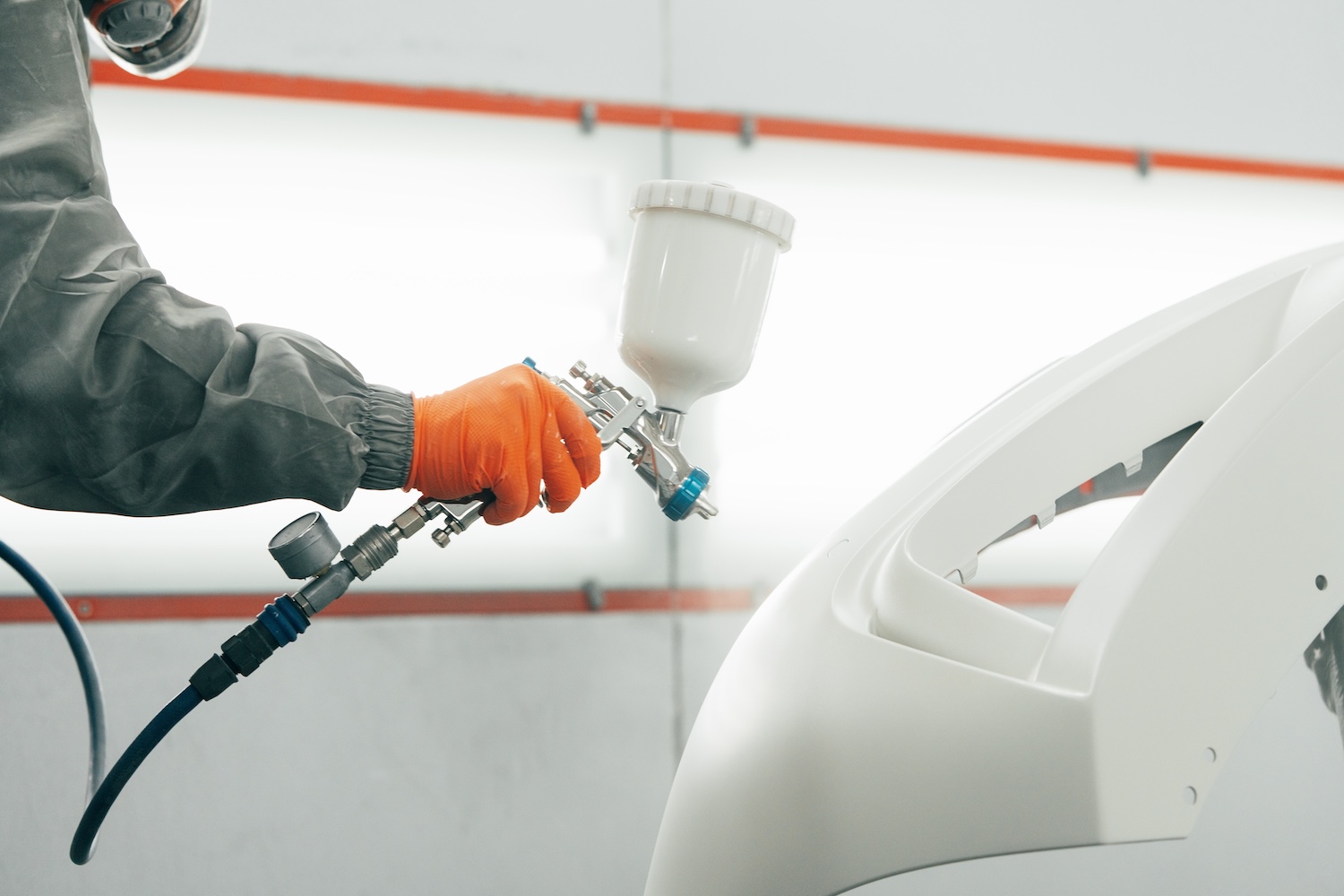A technician painting a front panel of a car with expert precision