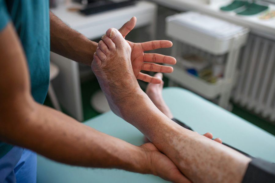 A podiatrist examines a diabetic patient’s foot in a clinical setting, assessing joint movement and foot structure as part of a professional foot evaluation.