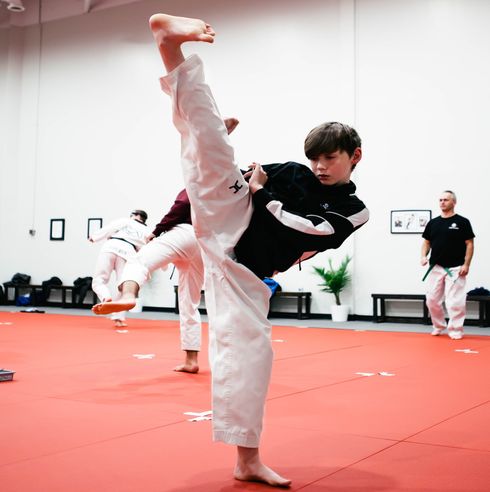 A teenager performing a Taekwondo turning kick