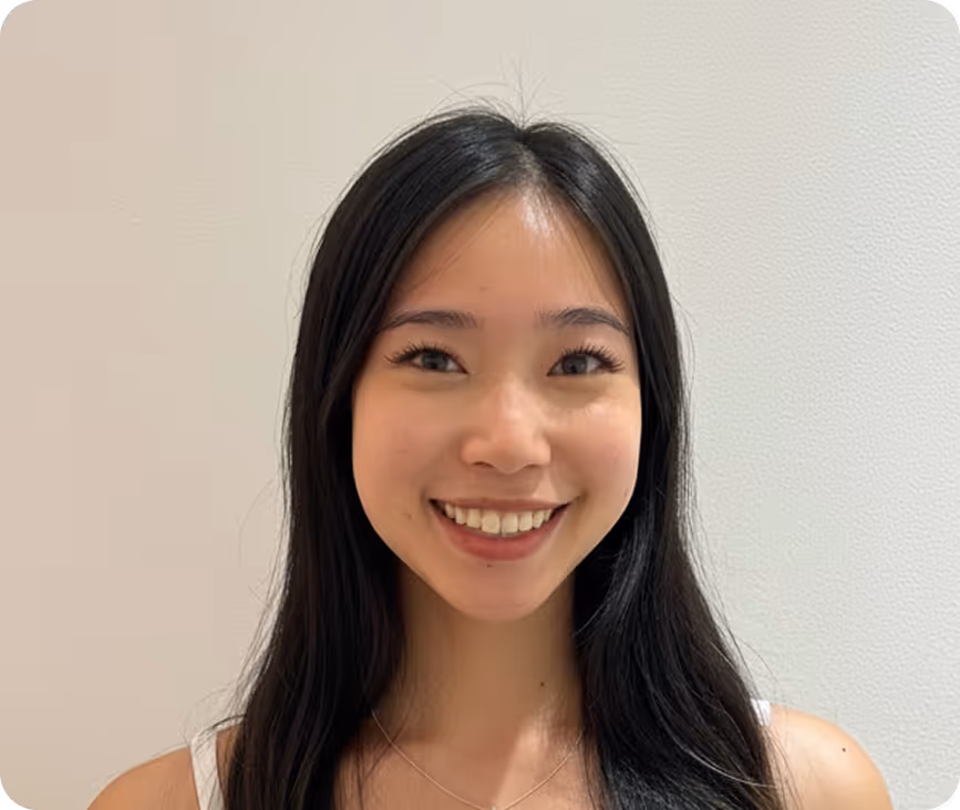 Smiling young woman with long black hair against a plain light background.