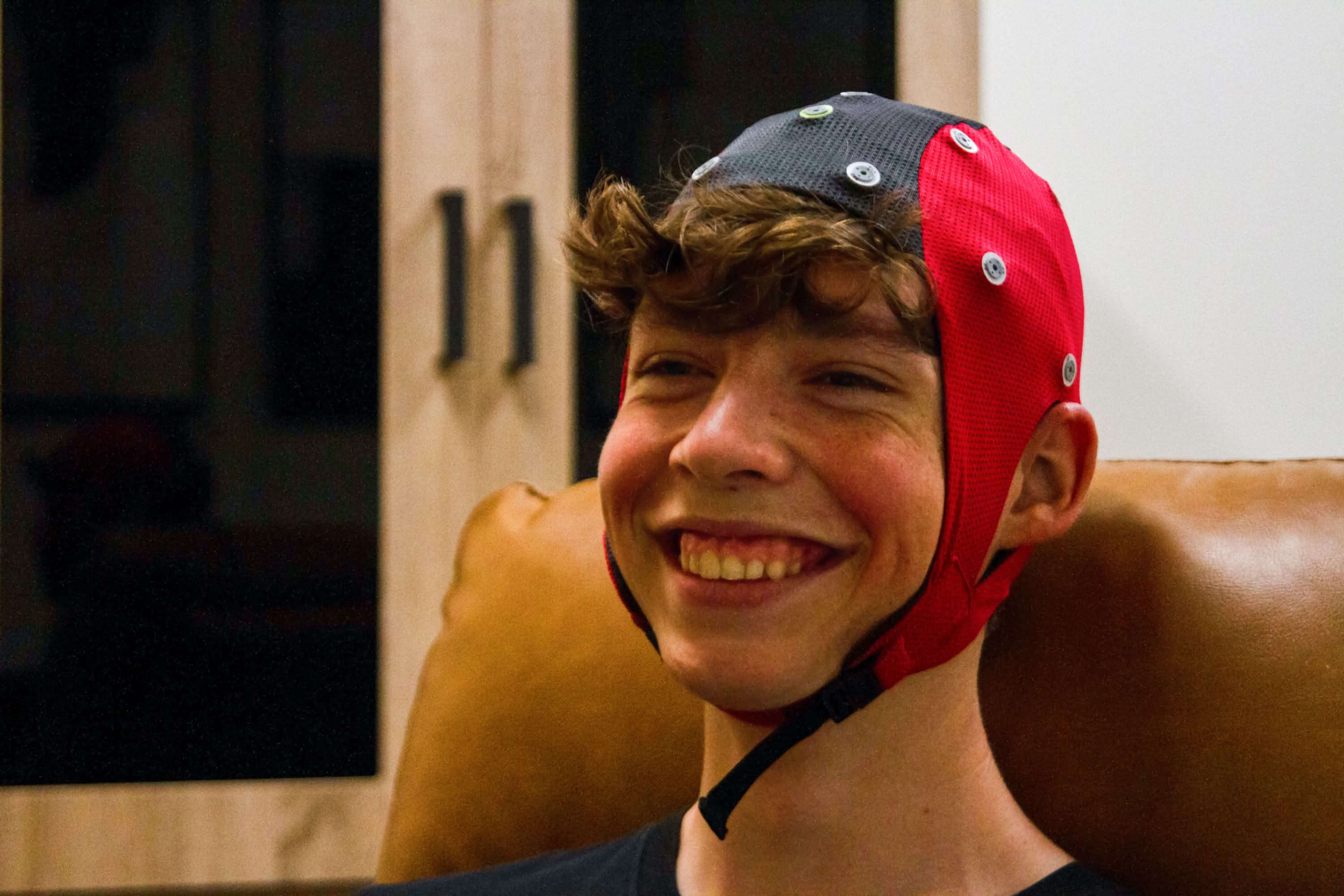 Brain Performance Neurofeedback Centers: Smiling person wearing red and black EEG cap