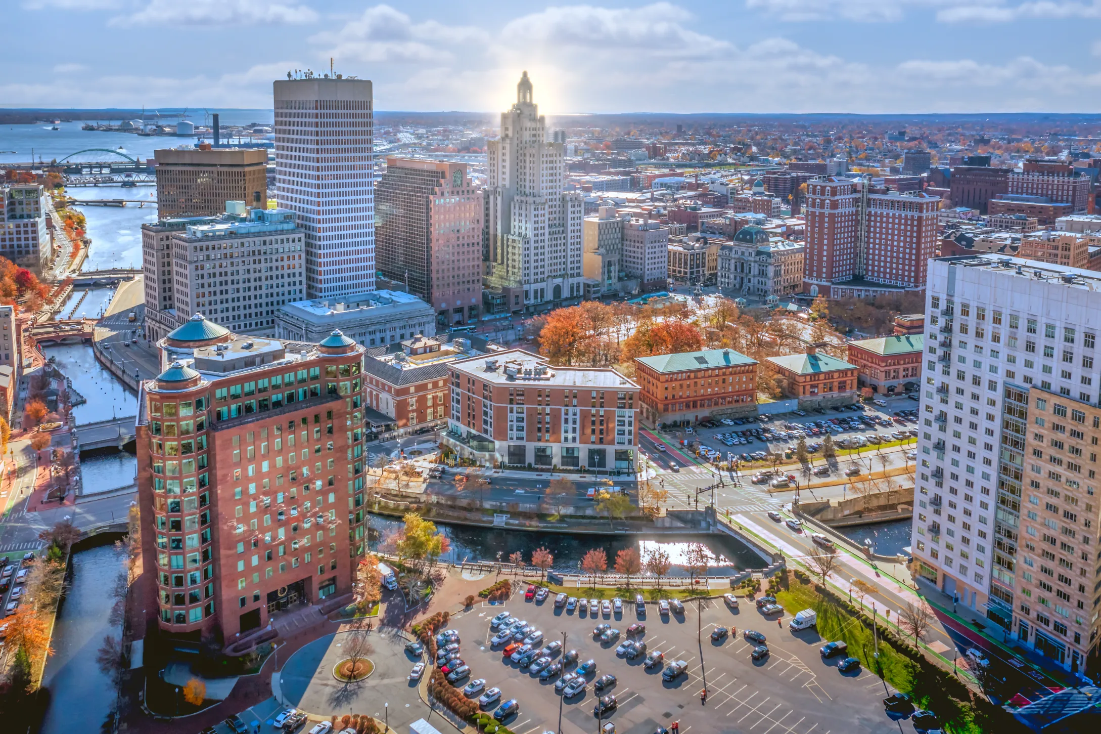 A scenic aerial view of downtown Providence, Rhode Island, featuring historic and modern buildings, waterways, and autumn foliage.