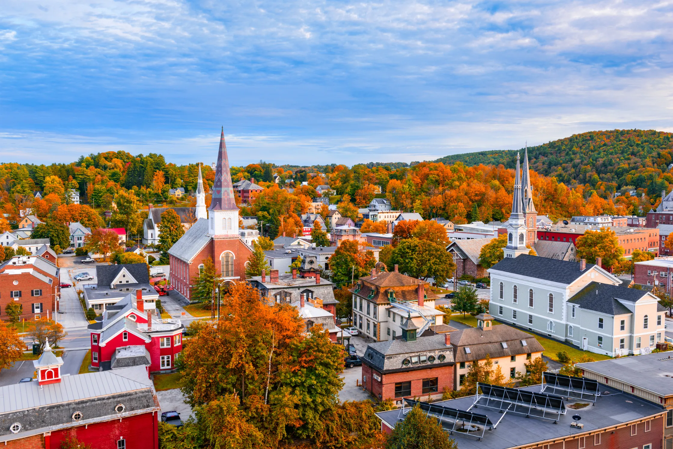 A charming autumn scene in a Vermont town, with colorful fall foliage, a historic red-brick church, and a quaint New England village setting.
