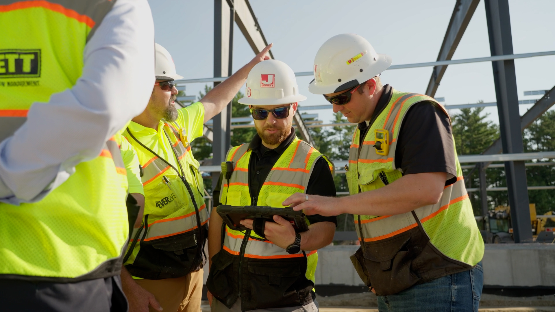 A close-up shot of architectural blueprints spread across a planning table, surrounded by construction tools and hard hats, emphasizing Jewett Construction’s integrated design-build approach that unifies planning and execution.
