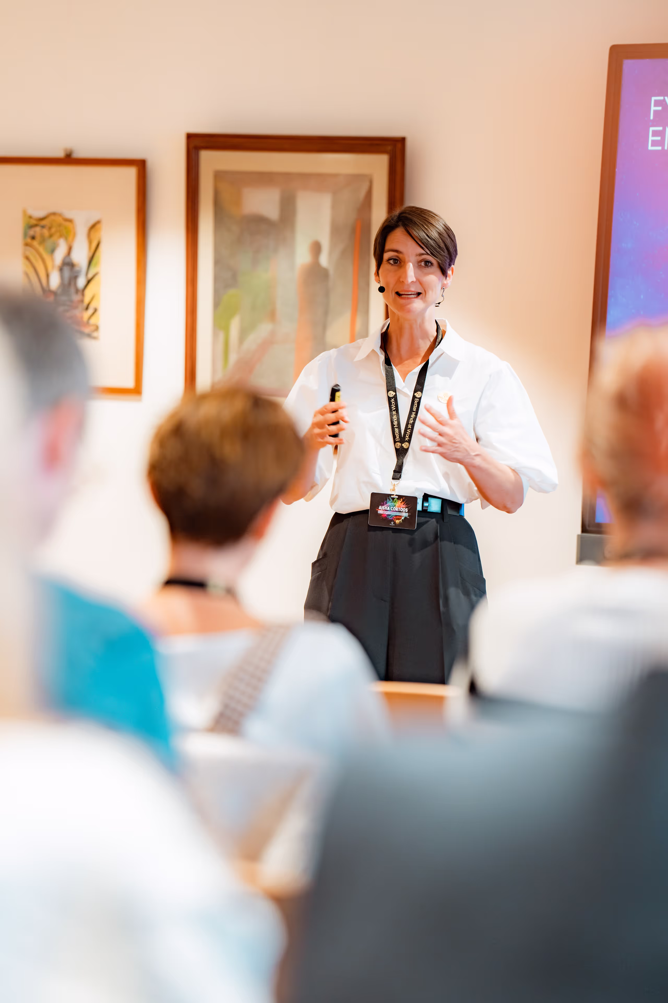 A middle aged man with grey hair and glasses talking to a black-haired woman.