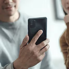 保護者の男性がスマートフォンを見ている様子