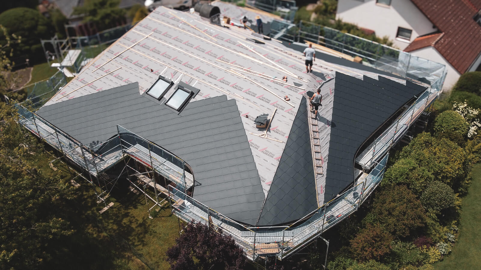 Drohnenaufnahmen während der Dachdeckerarbeiten mit Prefa Raute 44x44 Anthrazit, mit Dacheinteilung und geschwungenen Traufen