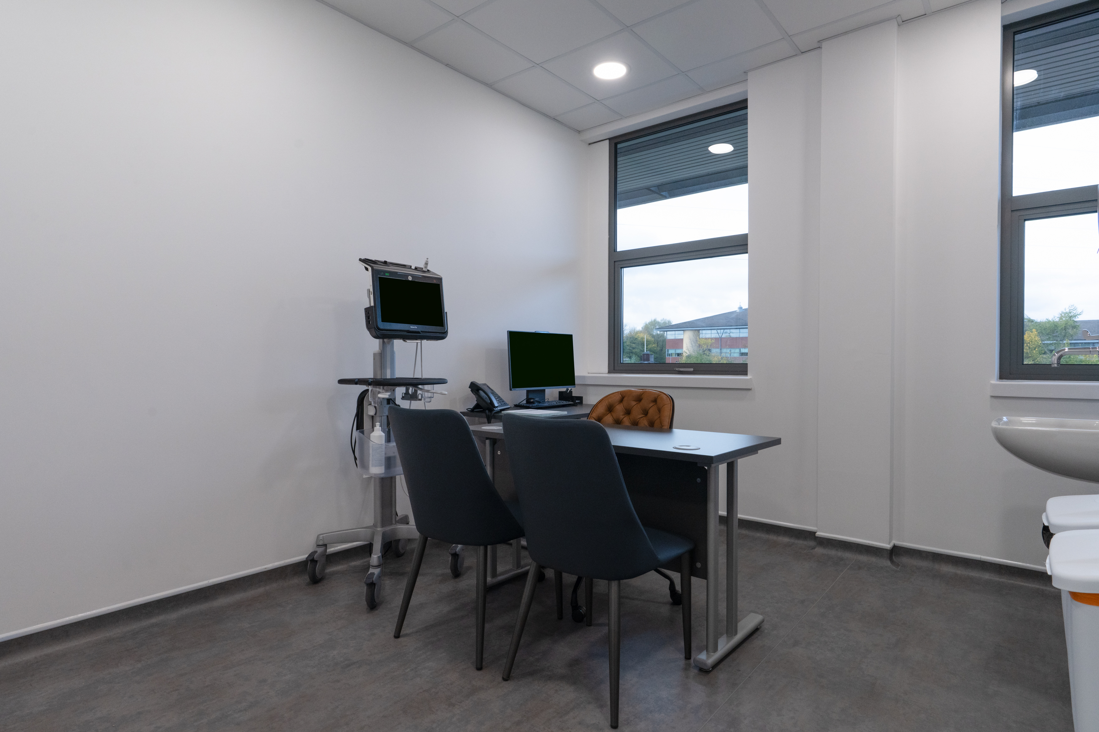 A photograph of consultation room 2 showing a L shaped desk with a computer and an ultrasound machine by the desk.