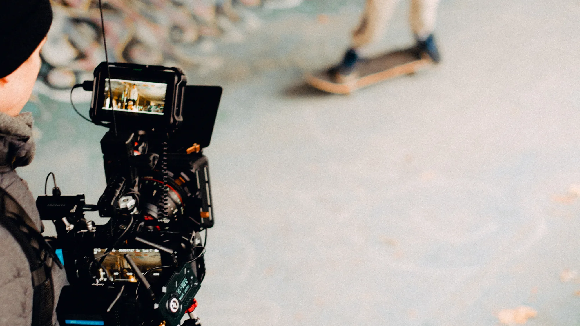 Operator filmujący deskorolkowca za pomocą profesjonalnej kamery.