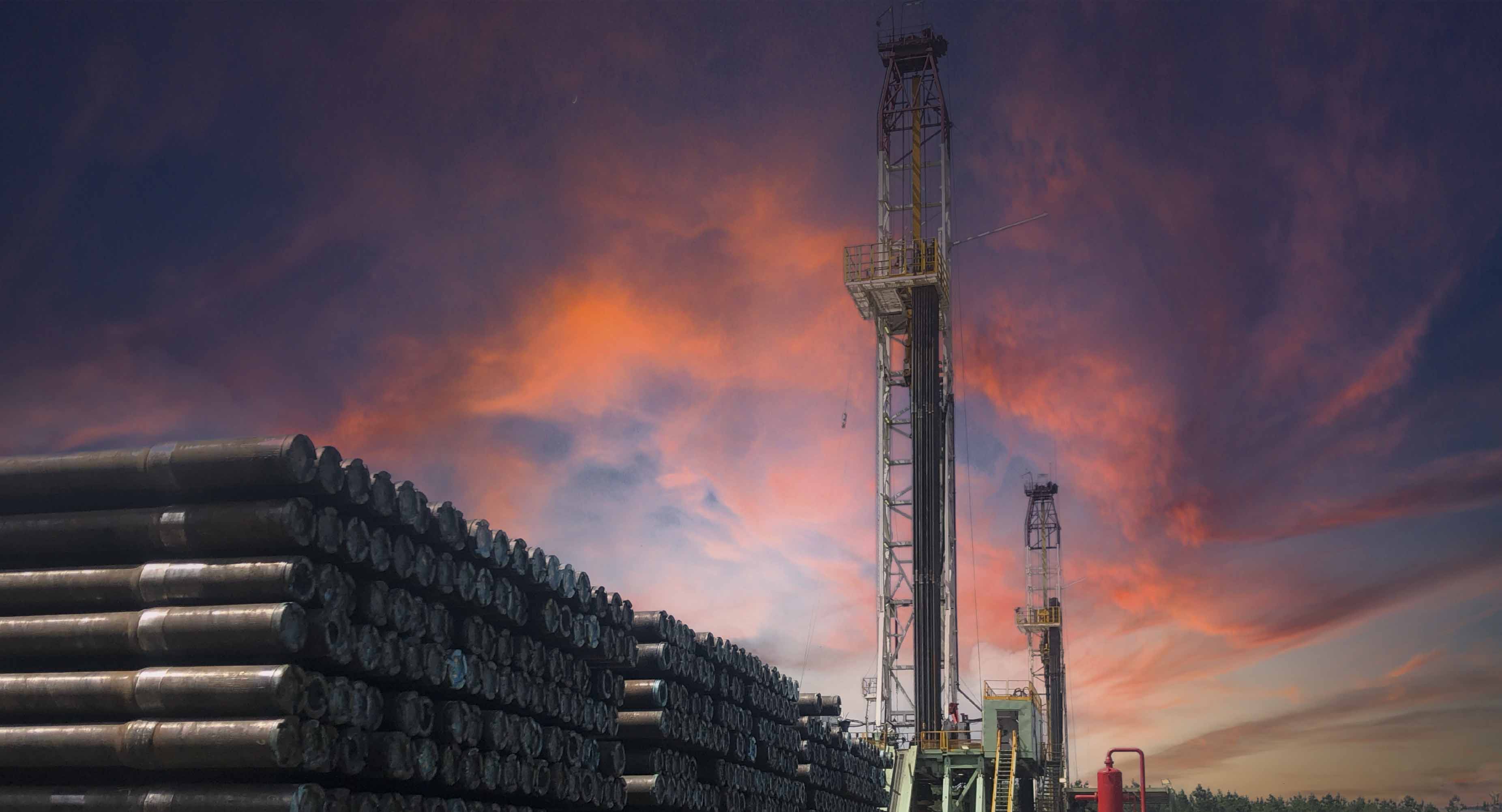 Oilfield drilling rig and stacked pipe under dramatic sunset sky in North Louisiana