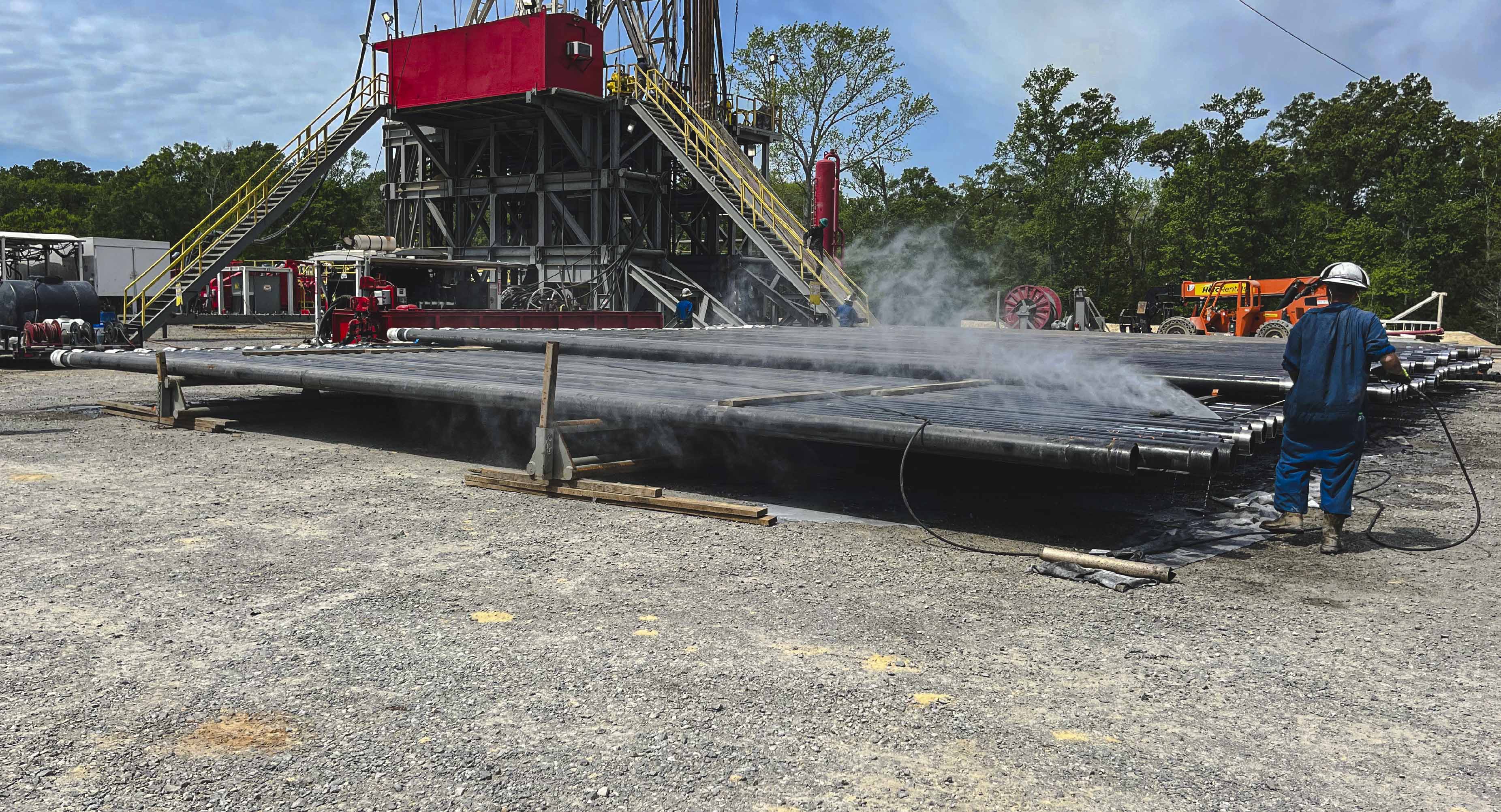 Cleared and graded gravel oilfield site in North Louisiana prepared for equipment staging and drilling operations, with work trucks visible on location